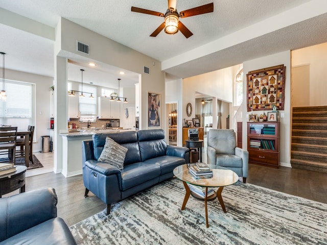 living room featuring a textured ceiling, dark wood-type flooring, and ceiling fan