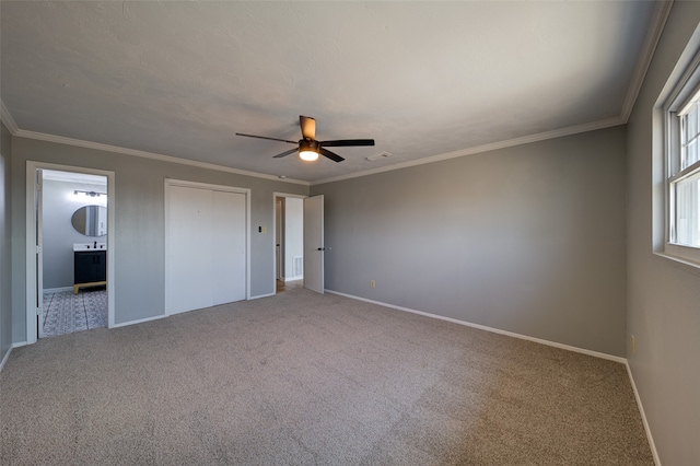 unfurnished bedroom featuring ceiling fan, crown molding, ensuite bath, and carpet flooring