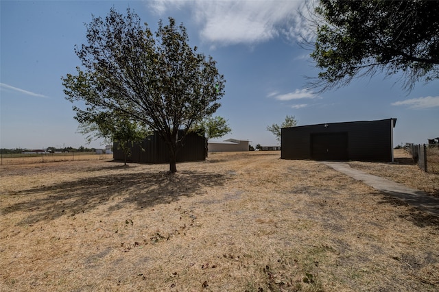 view of yard featuring a rural view, a garage, and an outbuilding