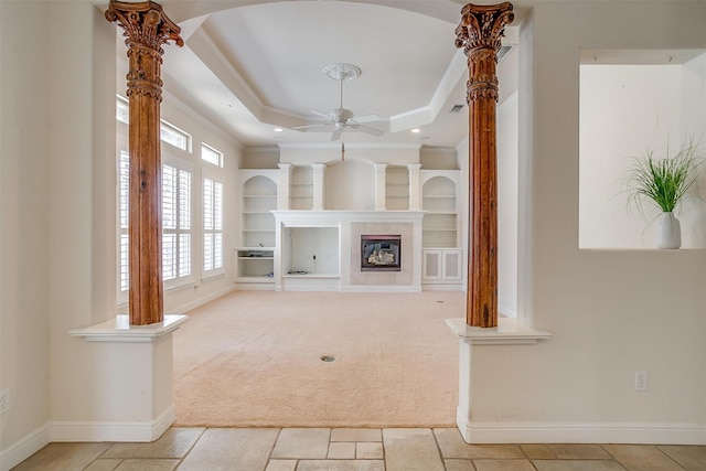 unfurnished living room with a fireplace, crown molding, a tray ceiling, ceiling fan, and light colored carpet