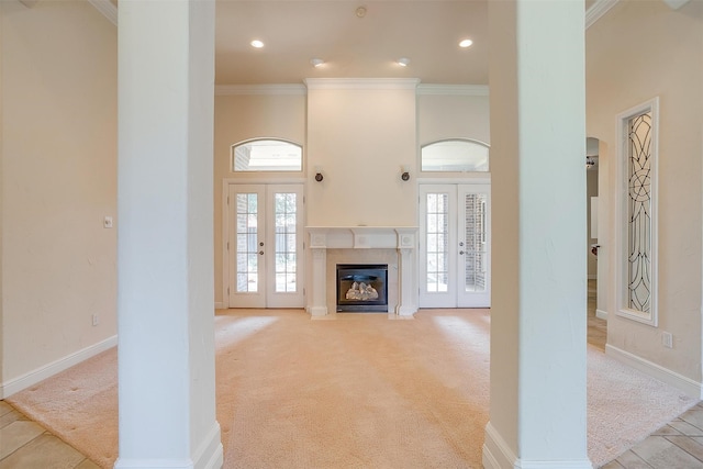 unfurnished living room featuring french doors, light colored carpet, crown molding, and a high ceiling