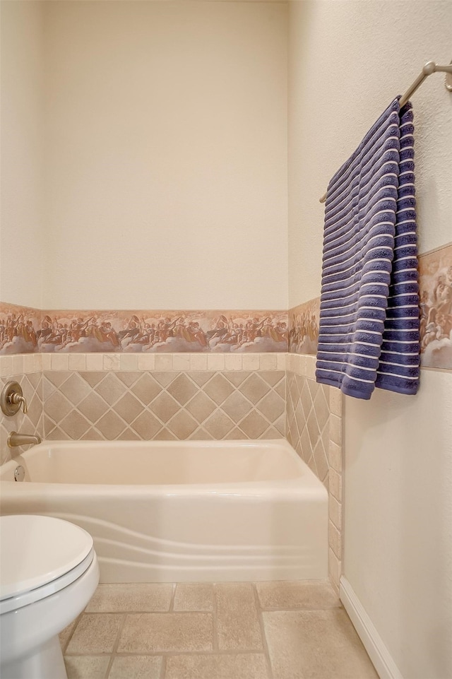 bathroom with a tub to relax in and toilet