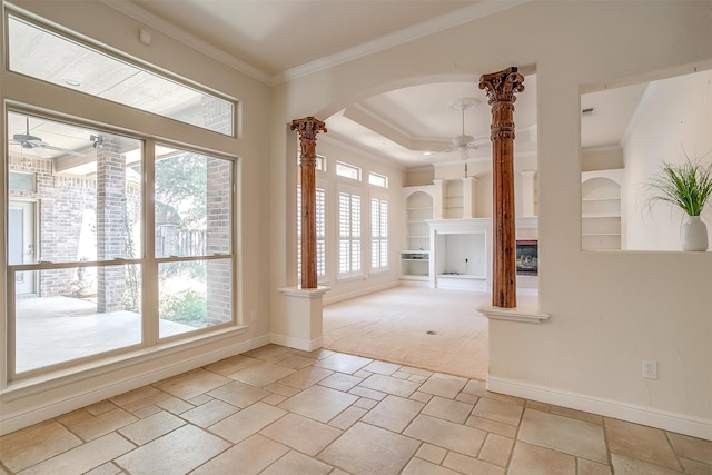 carpeted empty room featuring ceiling fan, a fireplace, built in features, and ornamental molding