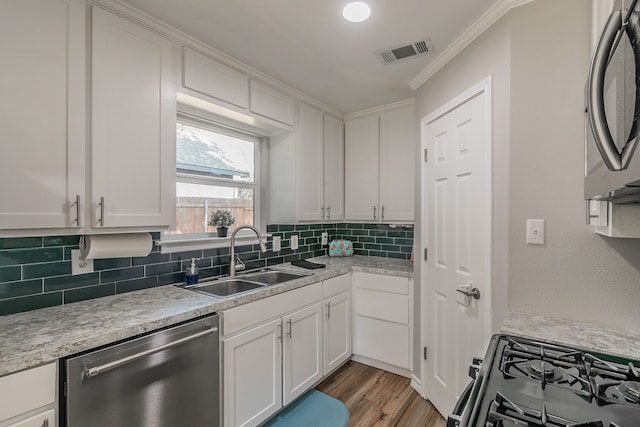 kitchen featuring stainless steel appliances, sink, white cabinetry, ornamental molding, and backsplash