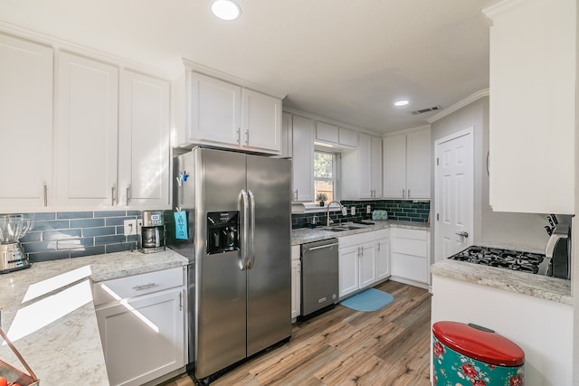 kitchen with crown molding, light hardwood / wood-style flooring, sink, white cabinets, and appliances with stainless steel finishes