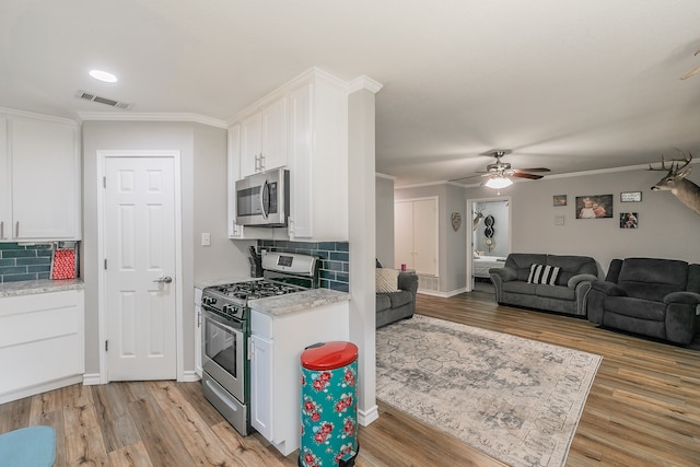 kitchen featuring decorative backsplash, white cabinets, appliances with stainless steel finishes, and light wood-type flooring