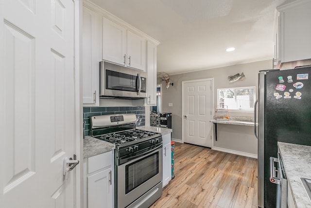 kitchen with light stone countertops, light hardwood / wood-style floors, crown molding, white cabinetry, and appliances with stainless steel finishes