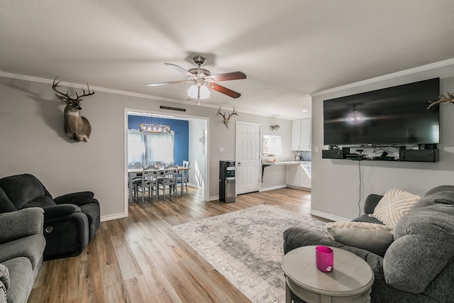 living room with ornamental molding, light wood-type flooring, and ceiling fan