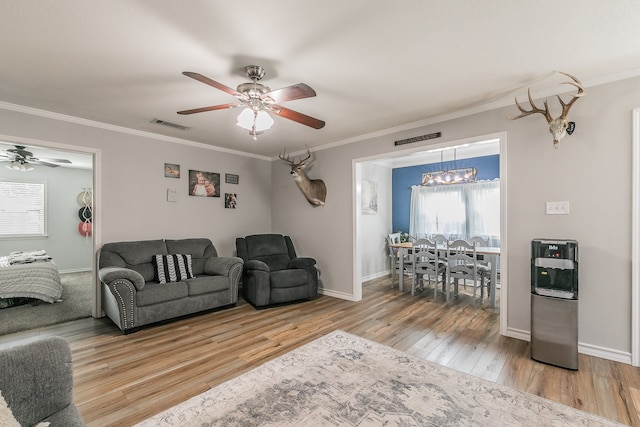 living room featuring heating unit, ceiling fan with notable chandelier, crown molding, and hardwood / wood-style flooring