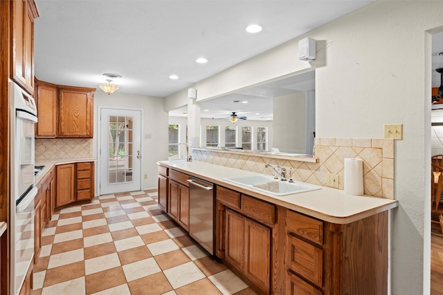 kitchen featuring sink, backsplash, stainless steel dishwasher, and oven