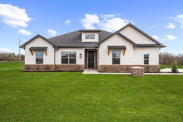 view of front of house featuring a front lawn, brick siding, and a shingled roof