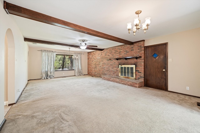 unfurnished living room with a brick fireplace, beamed ceiling, ceiling fan with notable chandelier, brick wall, and light colored carpet