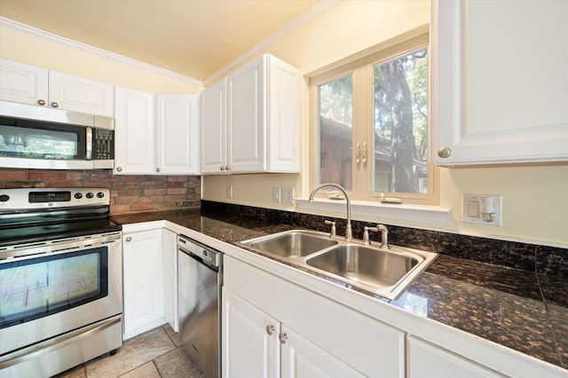 kitchen with white cabinetry, appliances with stainless steel finishes, light tile patterned flooring, and crown molding