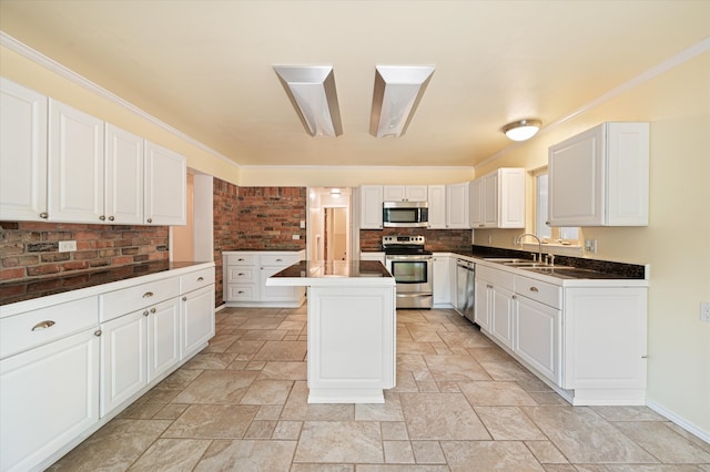 kitchen with light tile patterned floors, appliances with stainless steel finishes, a kitchen island, and white cabinetry