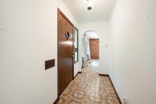 hallway featuring brick wall and tile patterned floors