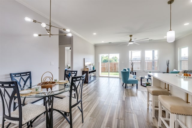 dining area with ceiling fan with notable chandelier, crown molding, and light hardwood / wood-style flooring