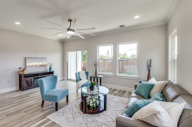 living room with crown molding, ceiling fan, and light hardwood / wood-style floors