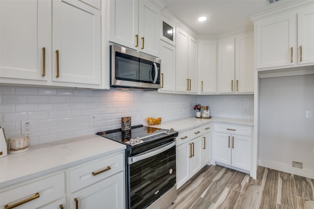 kitchen featuring stainless steel appliances, decorative backsplash, light wood-type flooring, and white cabinetry