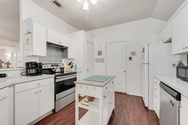 kitchen featuring appliances with stainless steel finishes, white cabinetry, dark hardwood / wood-style floors, tasteful backsplash, and vaulted ceiling