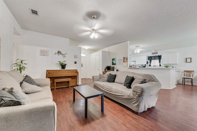 living room with a textured ceiling, ceiling fan, and wood-type flooring