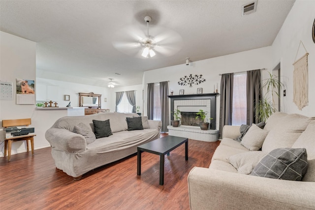 201 Anita Ln, Waxahachie, TX 75165 - living area with a ceiling fan, dark wood-style flooring, a brick fireplace, and a textured ceiling