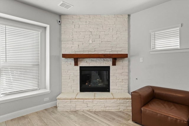 living room featuring a stone fireplace and light wood-type flooring