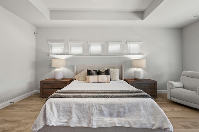 bedroom with a raised ceiling and light hardwood / wood-style floors