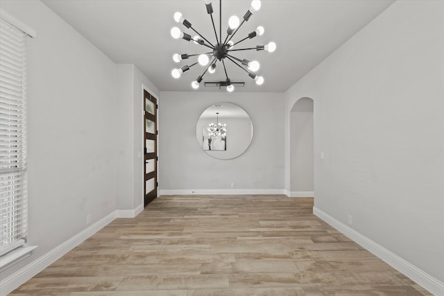 unfurnished dining area featuring an inviting chandelier and light hardwood / wood-style floors