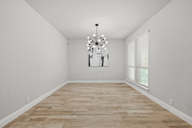 spare room with light hardwood / wood-style floors and a chandelier