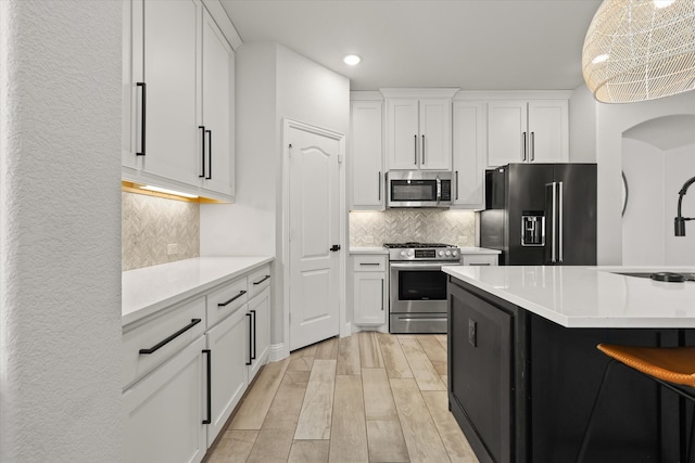 kitchen featuring appliances with stainless steel finishes, light wood-type flooring, backsplash, and white cabinetry