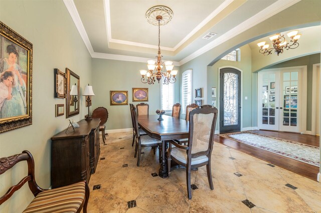 dining room featuring a chandelier, a tray ceiling, french doors, light hardwood / wood-style floors, and crown molding