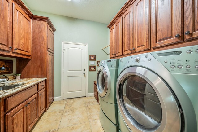 washroom featuring washing machine and clothes dryer, cabinets, and light tile patterned floors