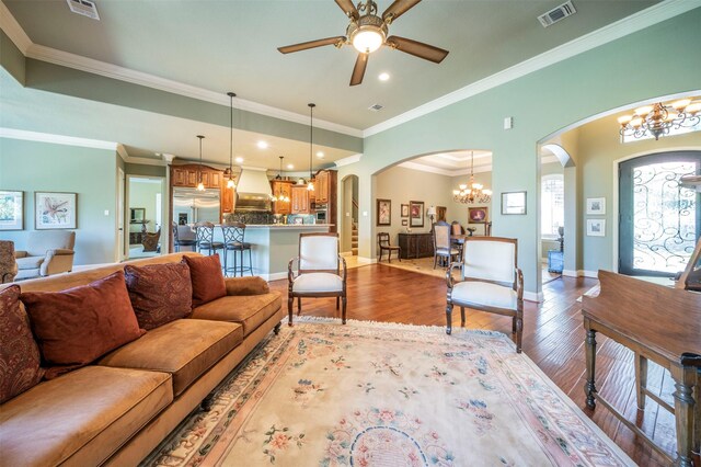 living room featuring ceiling fan with notable chandelier, wood-type flooring, and ornamental molding