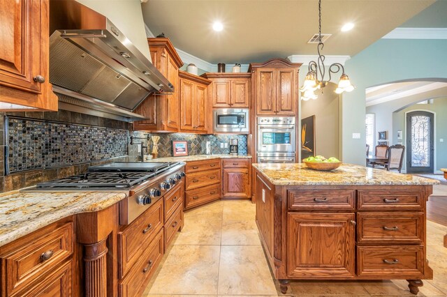 kitchen featuring backsplash, wall chimney exhaust hood, ornamental molding, light tile patterned floors, and stainless steel appliances