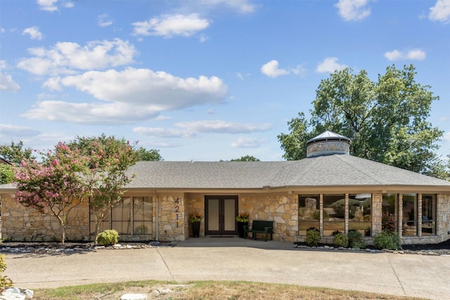 view of front of home featuring stone siding, a shingled roof, and french doors