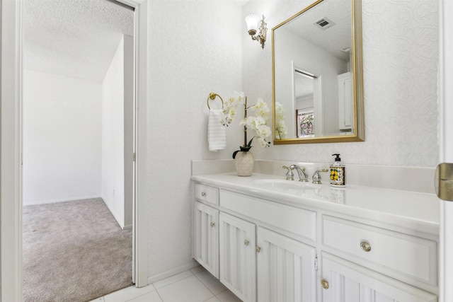 bathroom with a textured ceiling, tile patterned flooring, vanity, visible vents, and baseboards