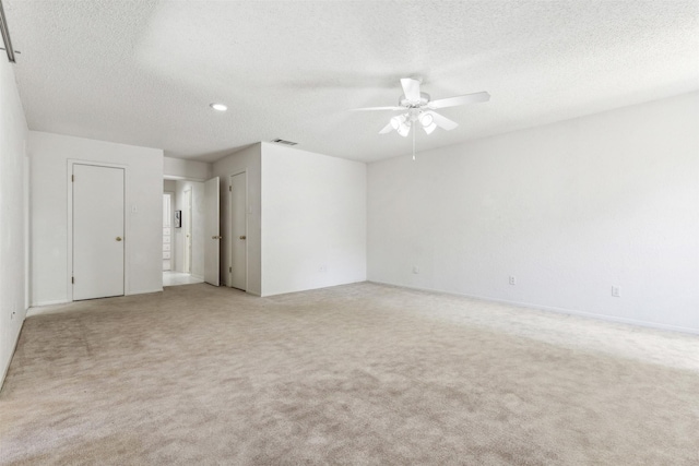 empty room with light carpet, a textured ceiling, visible vents, and a ceiling fan