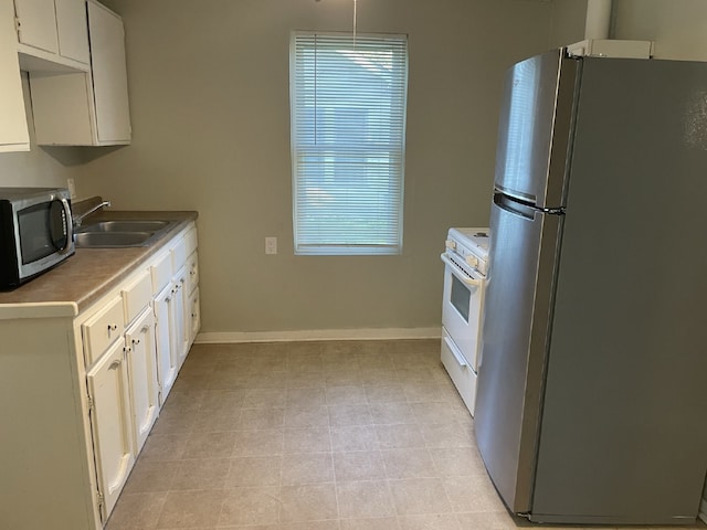 kitchen featuring appliances with stainless steel finishes, light tile patterned flooring, sink, and white cabinetry