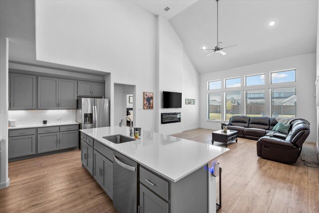 living room featuring a high ceiling, light wood-type flooring, and ceiling fan