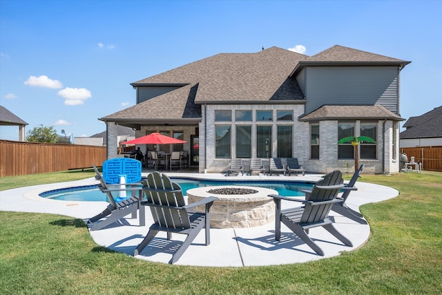 rear view of house with an outdoor fire pit, a fenced in pool, a yard, and a patio area