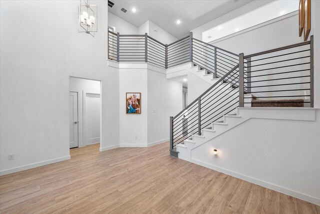 kitchen with light wood-type flooring, appliances with stainless steel finishes, a kitchen breakfast bar, and wall chimney exhaust hood