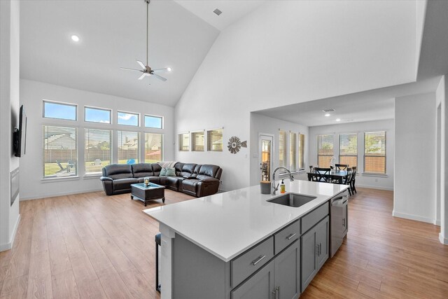 kitchen with gray cabinetry, light wood-type flooring, sink, wall chimney range hood, and tasteful backsplash