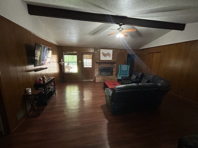 living room with vaulted ceiling with beams, wood walls, dark wood-type flooring, and a textured ceiling