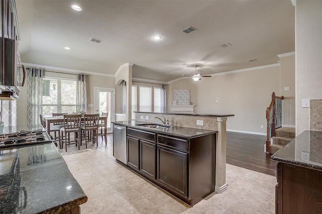 kitchen featuring light tile patterned flooring, sink, dark stone countertops, an island with sink, and crown molding