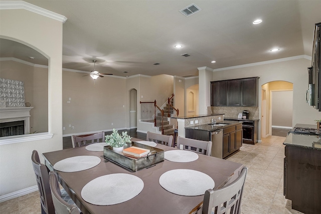 tiled dining space featuring ceiling fan, sink, and crown molding