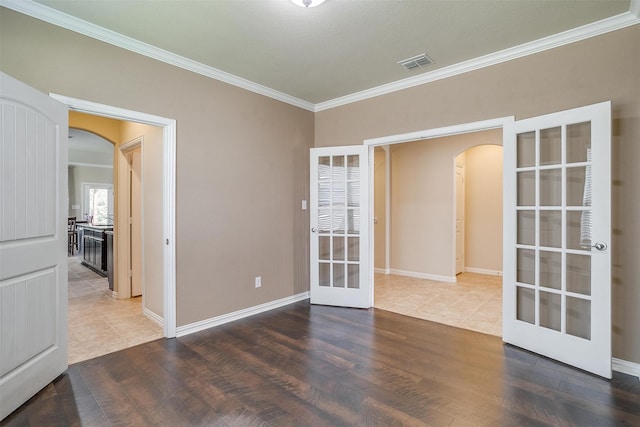 empty room featuring hardwood / wood-style flooring, french doors, and ornamental molding