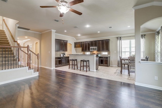 interior space featuring a kitchen breakfast bar, a center island, dark brown cabinetry, ceiling fan, and light tile patterned floors