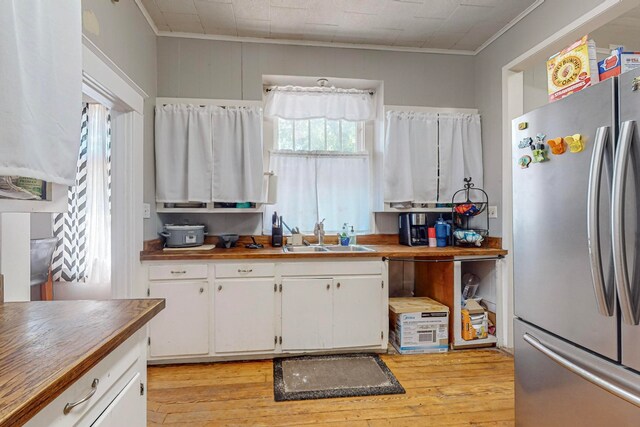 kitchen featuring sink, white cabinets, light hardwood / wood-style flooring, and stainless steel fridge