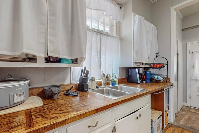 kitchen with white cabinetry, wooden counters, sink, and light hardwood / wood-style floors