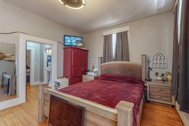 bedroom with light wood-type flooring and vaulted ceiling